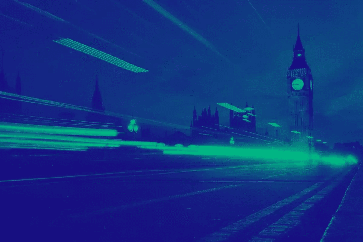 London skyline with Big Ben at night, featuring blue and green light trails from passing traffic.