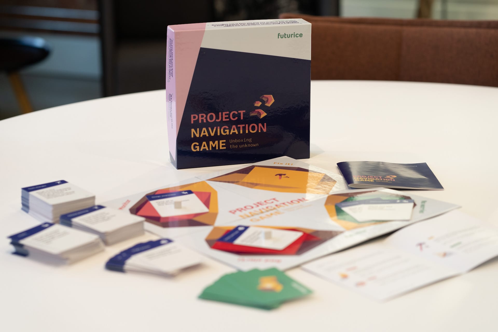 Project Navigation Game box with cards and game materials spread out on a white table, featuring colourful geometric designs.