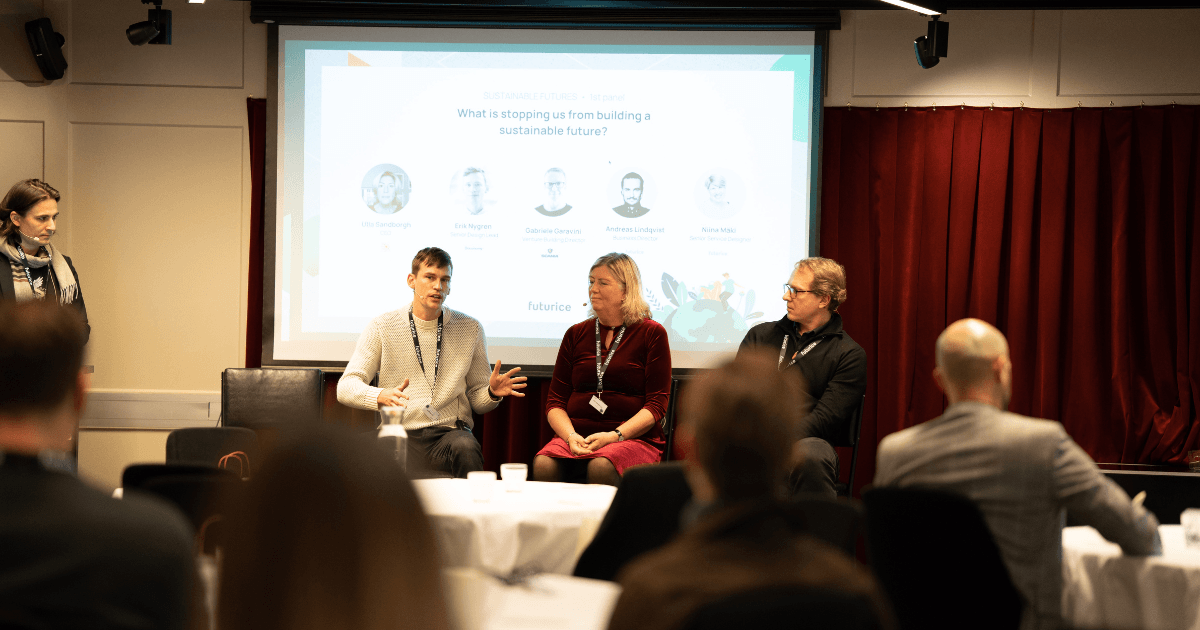 Panel discussion on sustainability with three speakers seated in front of a presentation about building a sustainable future.
